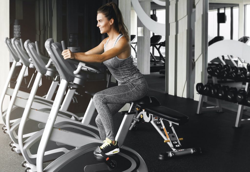 Building an Effective Workout Routine Cheerful woman is cycling on stationary bike during her cardio workout in the gym