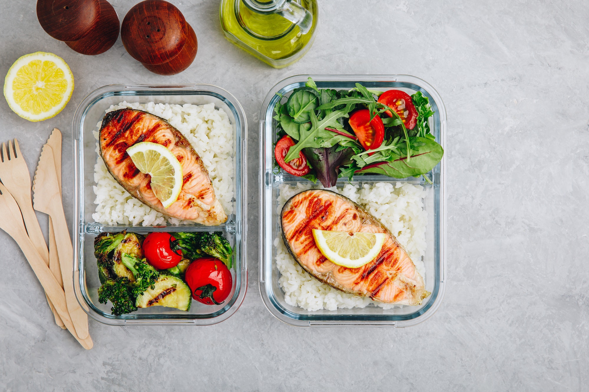 Meal prep containers with salmon and rice, green salad and baked vegetables.