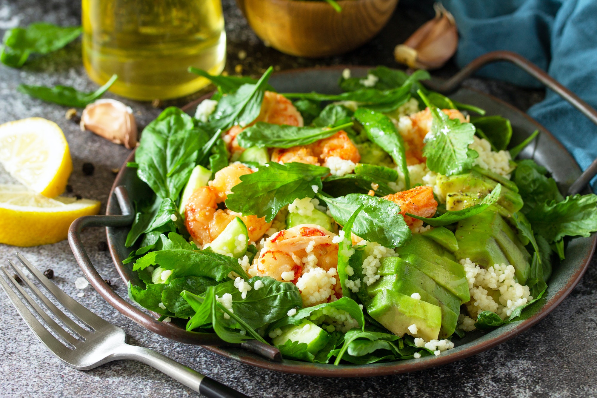 Healthy food. Dieting dinner close-up. Couscous salad with arugula, avocado and grilled shrimps.