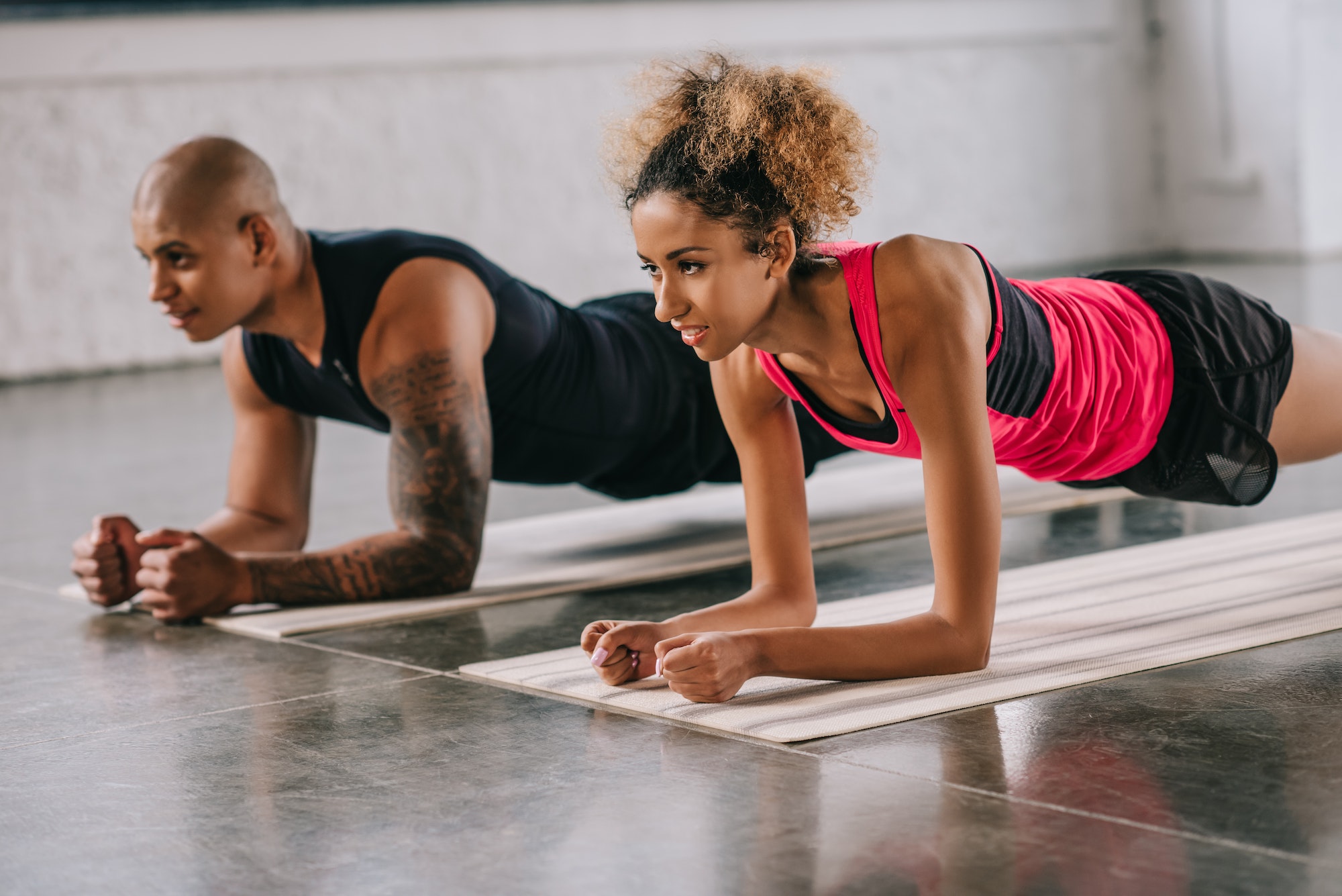 selective focus of african american couple of athletes doing plank on fitness mats at gym