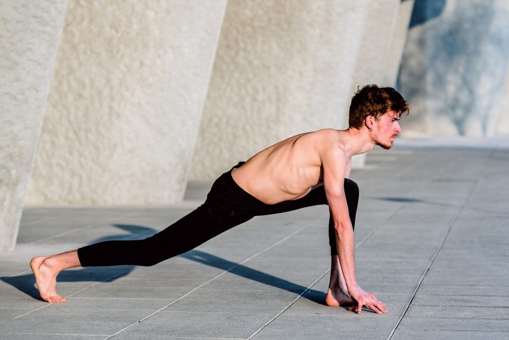 flexibility and mobility Young red-haired male athlete performing stretching after training to gain flexibility